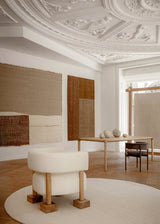 Modern interior design with a white ottoman, wooden table, and decorative elements.